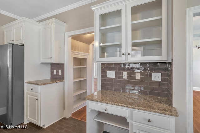 kitchen with stone counters, white cabinets, crown molding, and freestanding refrigerator