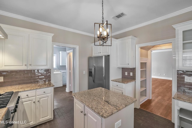 kitchen featuring visible vents, washer and dryer, white cabinetry, stainless steel fridge with ice dispenser, and brick floor