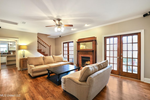 living room featuring a brick fireplace, dark wood-style floors, french doors, and visible vents