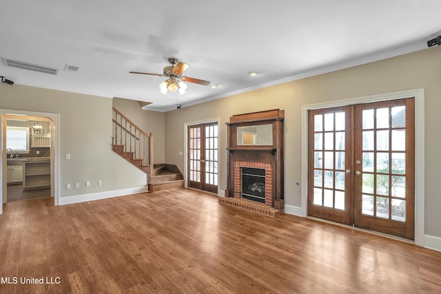 unfurnished living room with stairs, wood finished floors, french doors, and visible vents