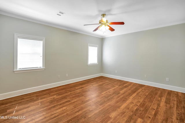 unfurnished room featuring crown molding, wood finished floors, baseboards, and visible vents