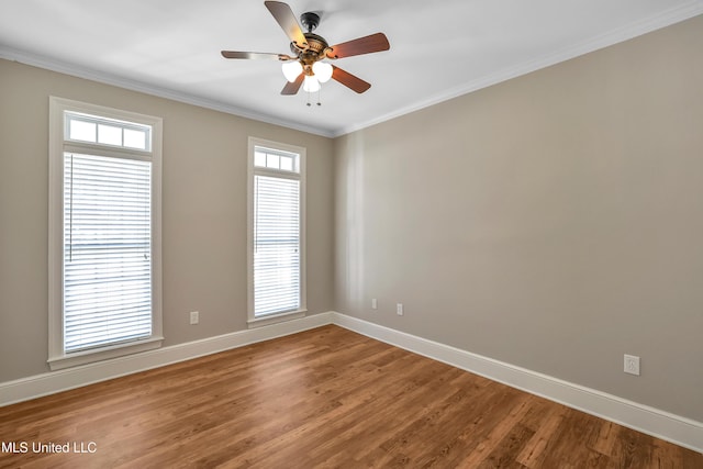 empty room with a ceiling fan, crown molding, wood finished floors, and baseboards