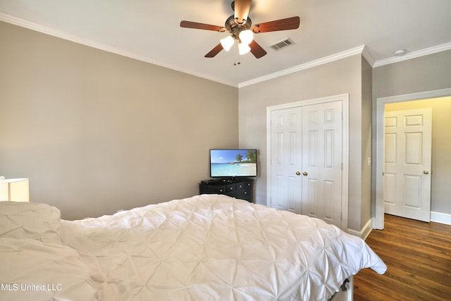 bedroom with visible vents, crown molding, baseboards, wood finished floors, and a closet