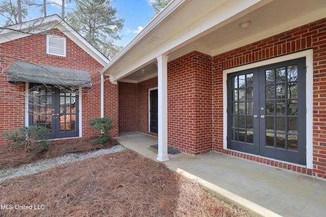 view of exterior entry featuring french doors and brick siding