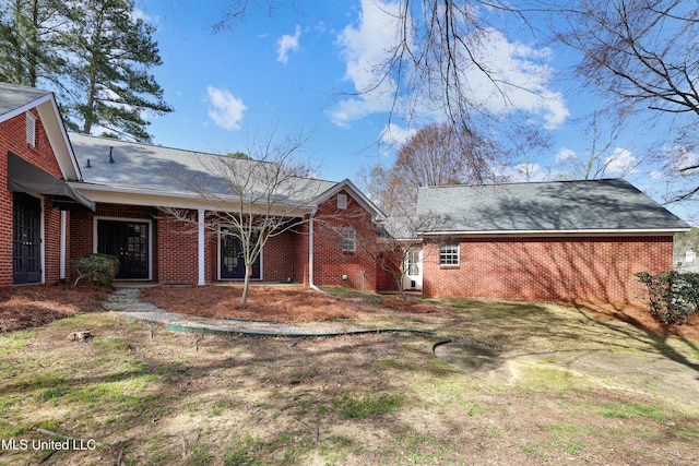 rear view of property with brick siding and roof with shingles