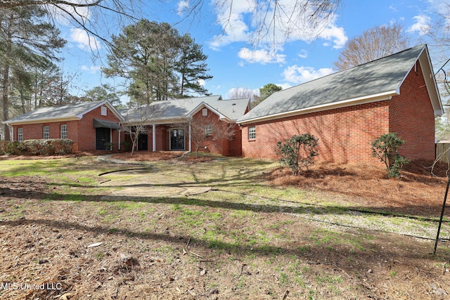 rear view of property with a yard and brick siding