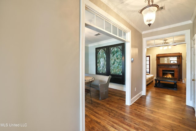 entrance foyer with wood finished floors, visible vents, baseboards, a fireplace, and crown molding