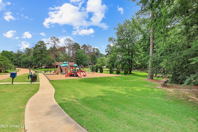 view of property's community featuring playground community and a yard