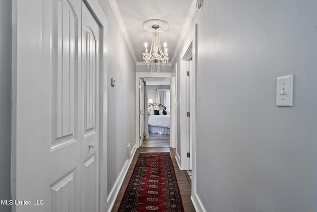 corridor featuring ornamental molding, dark wood-type flooring, and a notable chandelier