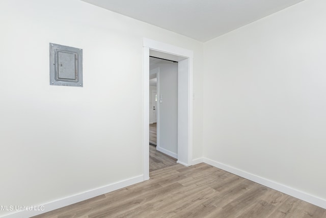 spare room featuring electric panel and light wood-type flooring