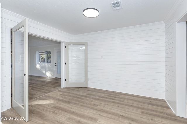 unfurnished room featuring hardwood / wood-style floors, crown molding, and wooden walls