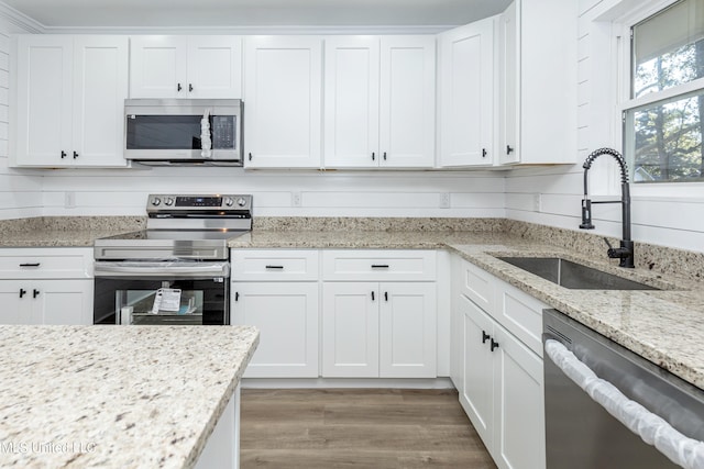 kitchen with sink, appliances with stainless steel finishes, light hardwood / wood-style flooring, and white cabinets