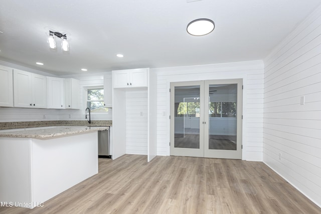 kitchen with light stone countertops, sink, white cabinetry, and light hardwood / wood-style floors