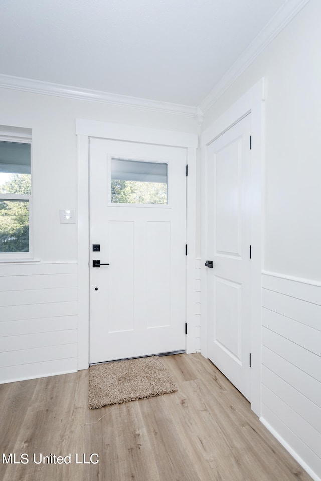 foyer featuring a wealth of natural light, ornamental molding, and light hardwood / wood-style floors