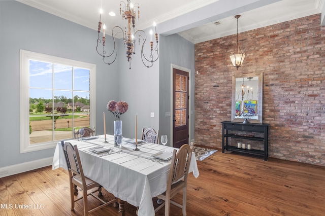 dining space with baseboards, brick wall, an inviting chandelier, and wood finished floors