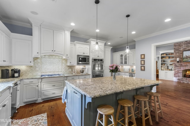 kitchen with a kitchen island, dark wood finished floors, a breakfast bar, stainless steel appliances, and white cabinetry