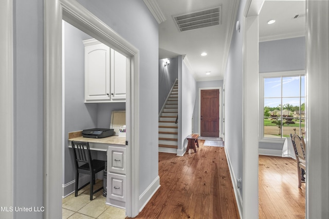 hallway featuring visible vents, ornamental molding, baseboards, stairway, and light wood-type flooring