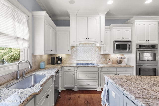 kitchen featuring white cabinets, light stone countertops, appliances with stainless steel finishes, and a sink