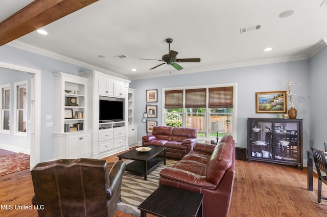 living area with ceiling fan, ornamental molding, and wood finished floors