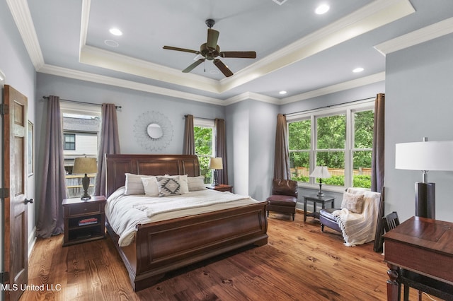 bedroom with ornamental molding, a raised ceiling, a ceiling fan, and wood finished floors
