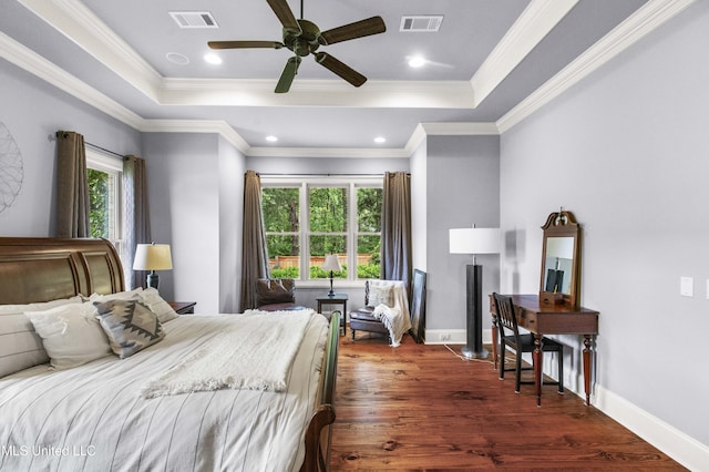 bedroom with a tray ceiling, dark wood finished floors, and visible vents