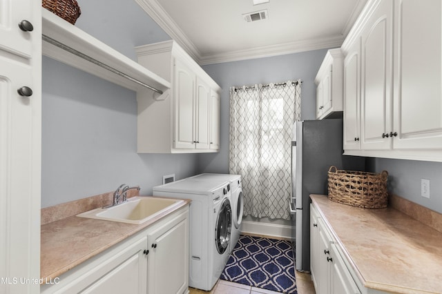 laundry area with cabinet space, crown molding, a sink, visible vents, and washer and clothes dryer