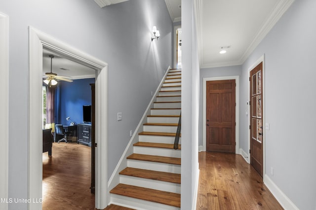 staircase featuring baseboards, ornamental molding, ceiling fan, and wood finished floors
