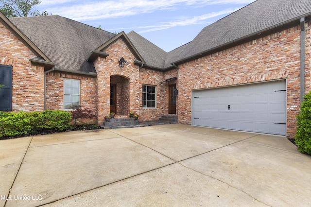 french provincial home with brick siding, driveway, roof with shingles, and a garage