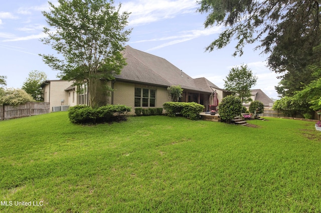 exterior space with fence, a lawn, and brick siding