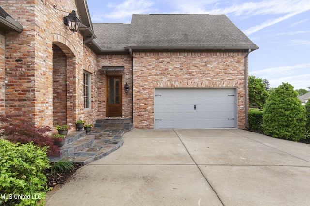 view of front facade with concrete driveway, brick siding, an attached garage, and roof with shingles