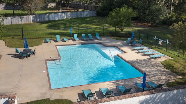 pool with a patio, a lawn, and fence
