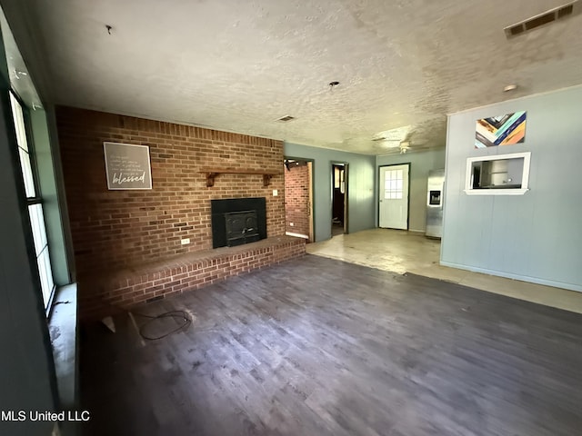 unfurnished living room featuring wood finished floors, baseboards, and a textured ceiling