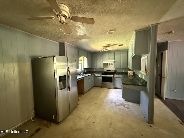 kitchen featuring appliances with stainless steel finishes, dark countertops, a sink, ceiling fan, and a textured ceiling