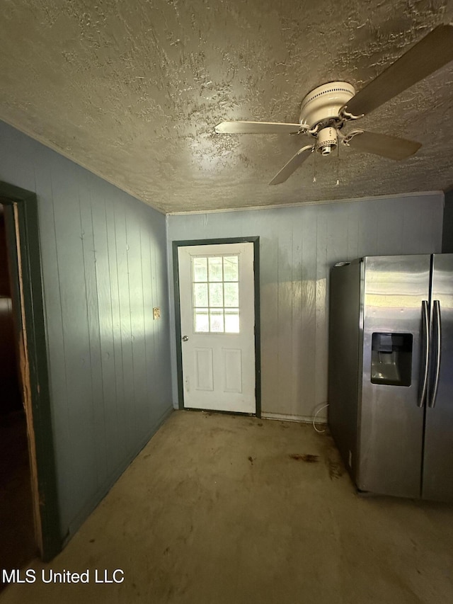 entryway featuring a textured ceiling, ceiling fan, carpet, and wood walls
