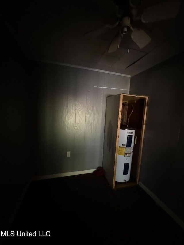carpeted spare room featuring ceiling fan, electric water heater, and baseboards