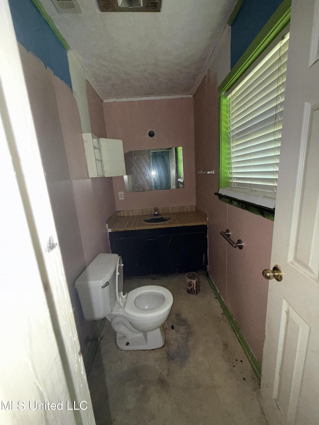 half bath featuring a sink, toilet, unfinished concrete floors, and a textured ceiling