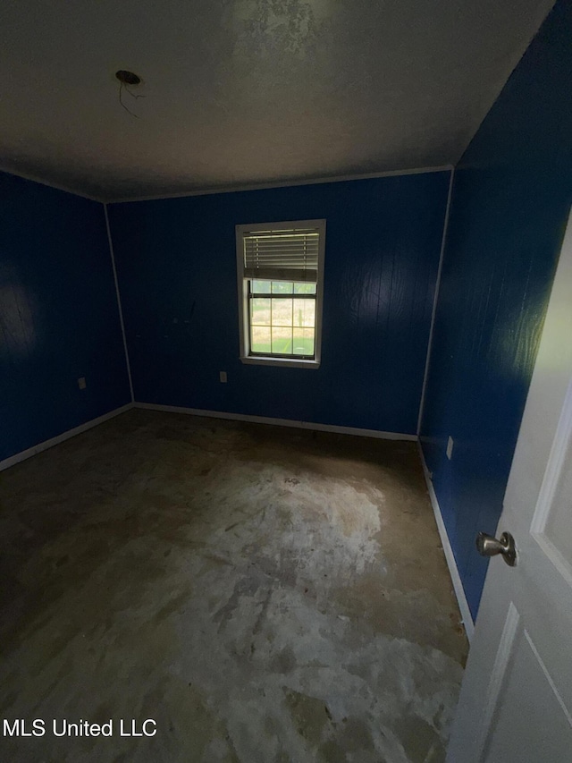 empty room with unfinished concrete floors and baseboards