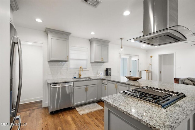 kitchen with island exhaust hood, sink, gray cabinetry, and appliances with stainless steel finishes