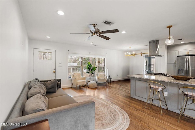 living room with ceiling fan with notable chandelier and wood-type flooring