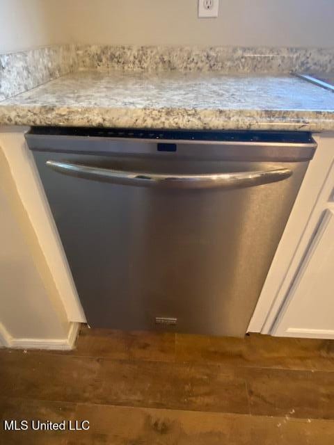 interior details with wood finished floors, stainless steel dishwasher, and white cabinets