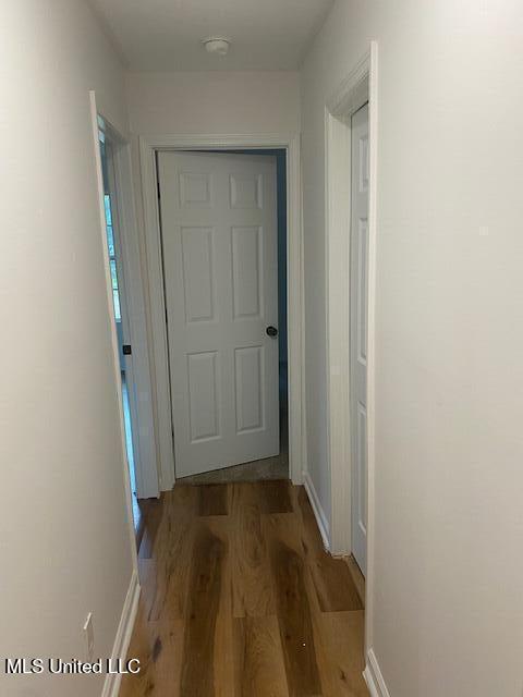 corridor with baseboards and wood finished floors