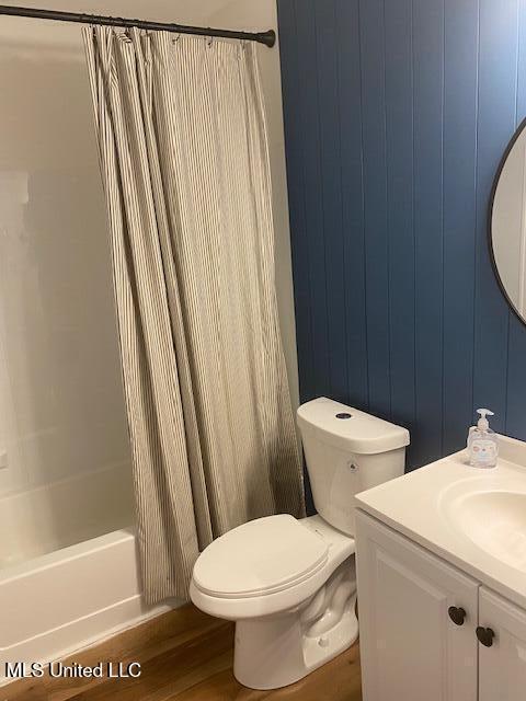 full bathroom with shower / bath combo with shower curtain, wood finished floors, toilet, and vanity