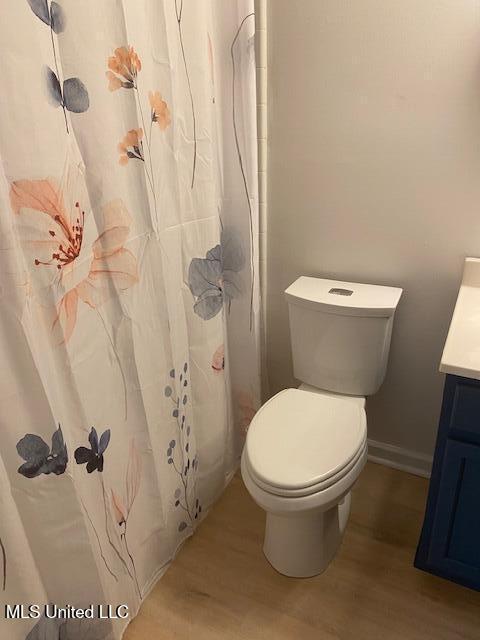 full bathroom featuring toilet, vanity, wood finished floors, and baseboards