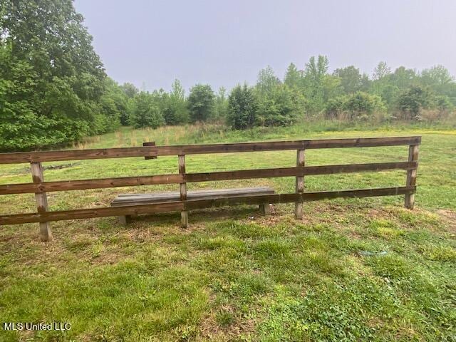 view of gate featuring a rural view, a yard, and a wooded view