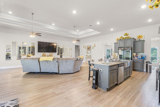 kitchen with a large island with sink, appliances with stainless steel finishes, light hardwood / wood-style flooring, and hanging light fixtures