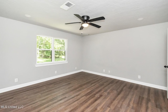 spare room featuring a ceiling fan, dark wood finished floors, visible vents, and baseboards