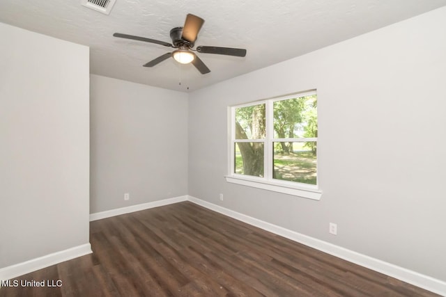 empty room with a textured ceiling, ceiling fan, dark wood-style flooring, visible vents, and baseboards