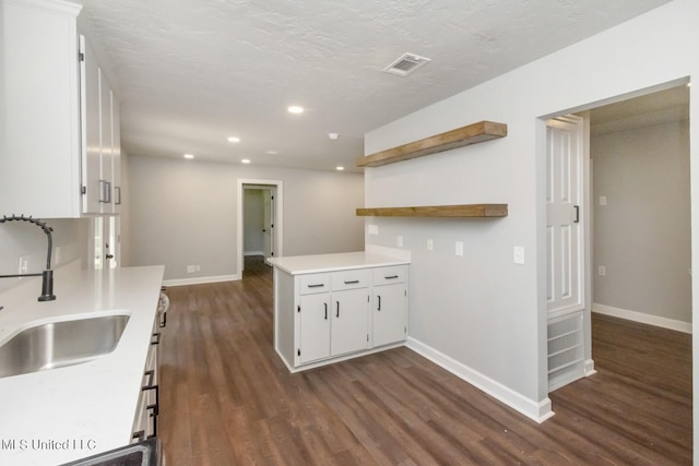 kitchen featuring dark wood finished floors, open shelves, light countertops, white cabinets, and a sink