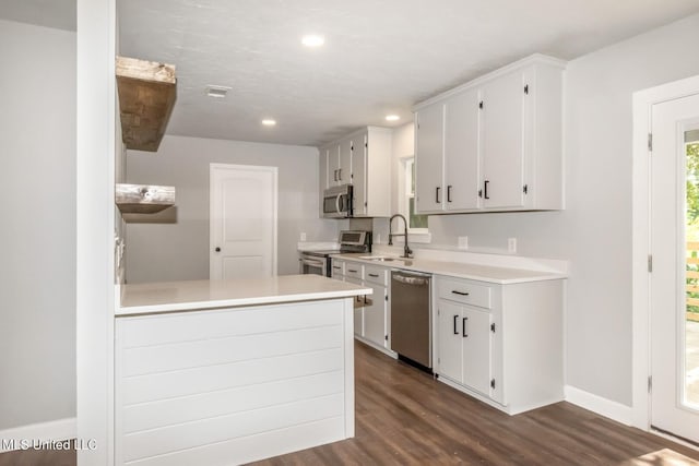 kitchen featuring dark wood-type flooring, stainless steel appliances, a sink, and light countertops