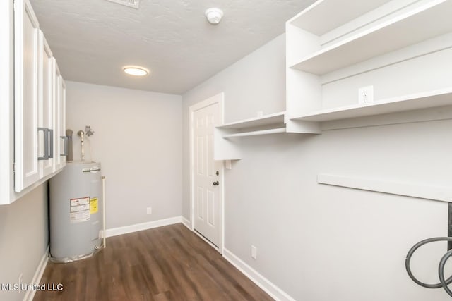 clothes washing area featuring dark wood-style floors, water heater, baseboards, and a textured ceiling